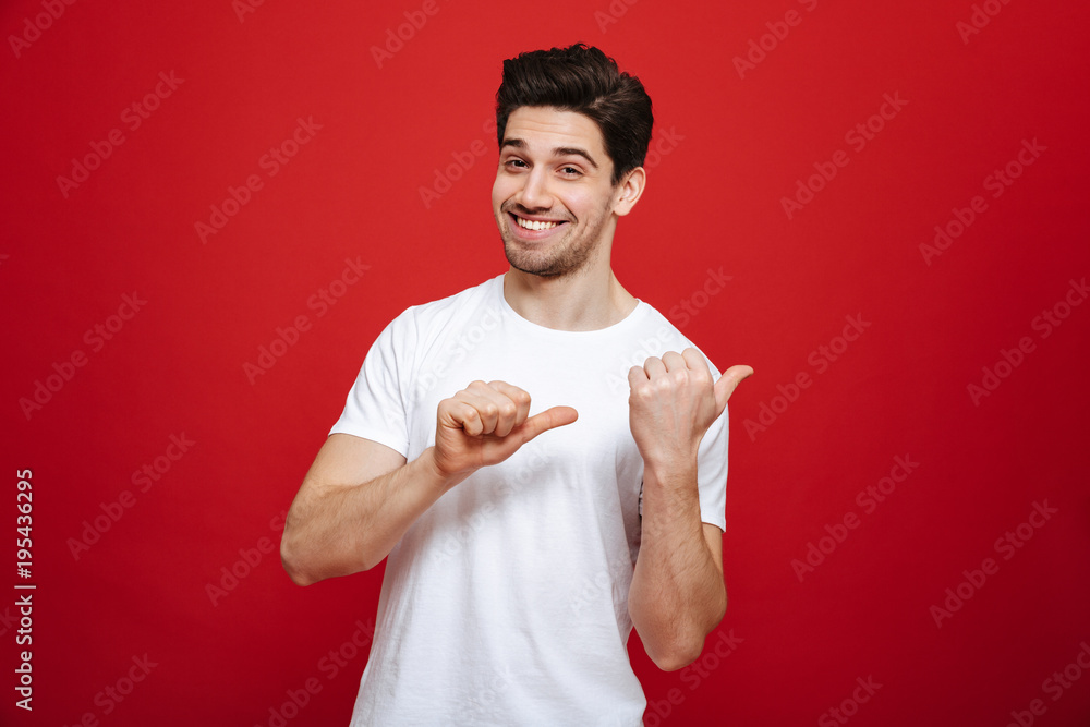 Portrait of a happy young man in white t-shirt pointing Portrait of a happy young man in white t-shirt pointing