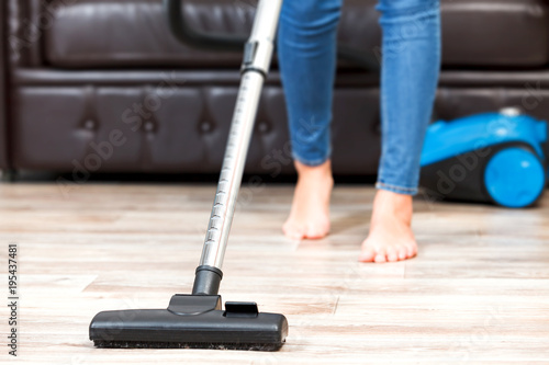 Young woman vacuum cleaning the apartment, housework