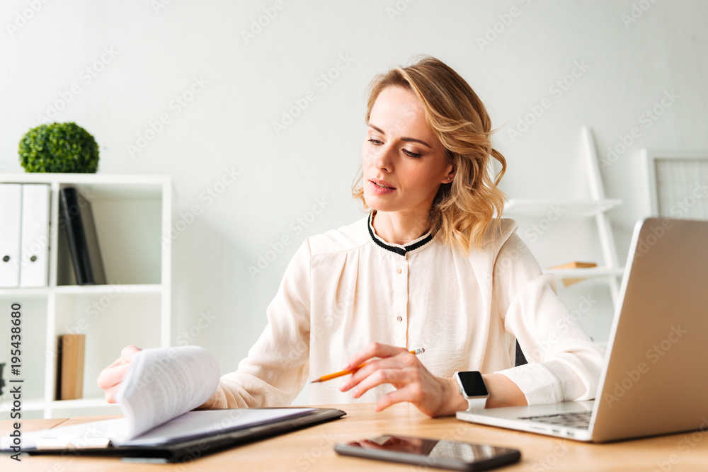 Serious young business woman sitting in office Serious young business woman sitting in office