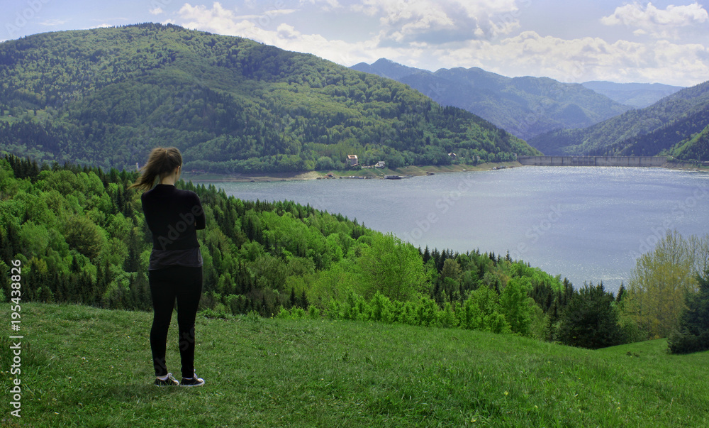 young woman admiring beautiful landscape with Bicaz lake in Romanian Carpathian mountains