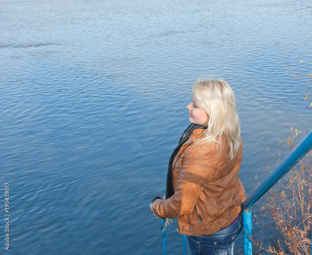 Blonde young girl by the river. Autumn Sunny day Blonde young girl by the river. Autumn Sunny day