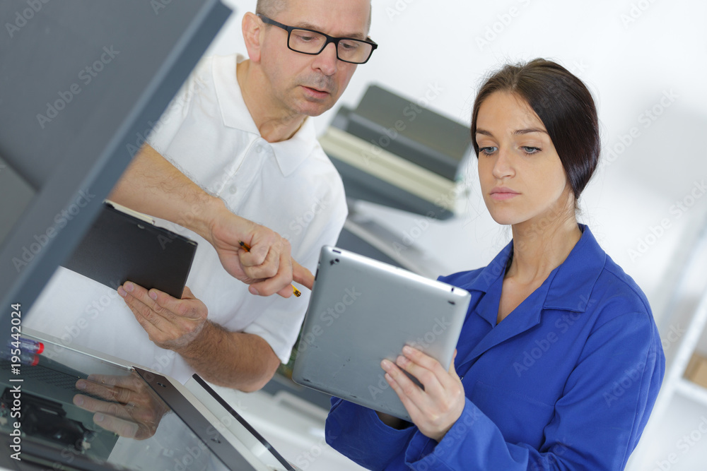 young female mechanic using a tablet with manager young female mechanic using a tablet with manager
