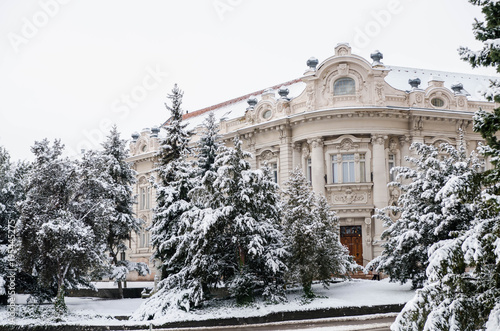 Old baroque building with pines in the garden covered with snow