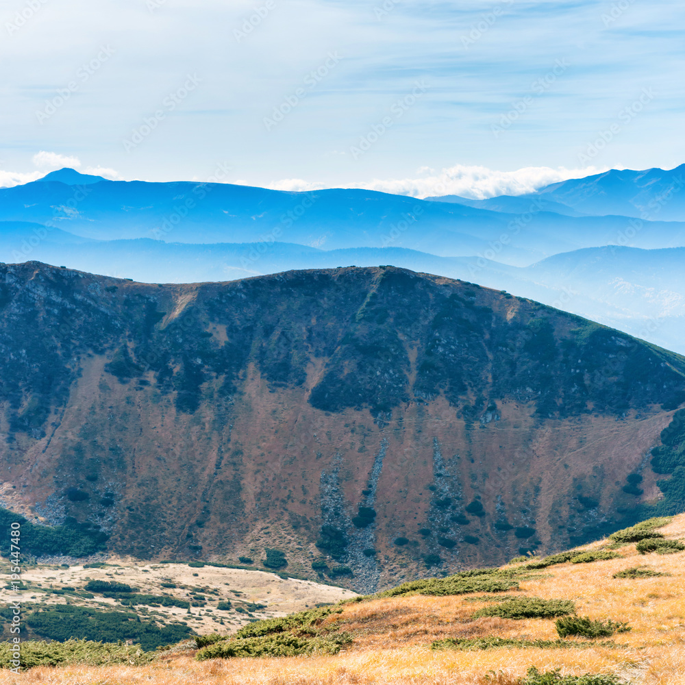 Fototapeta premium Mountains landscape with field of dry grass and blue sky