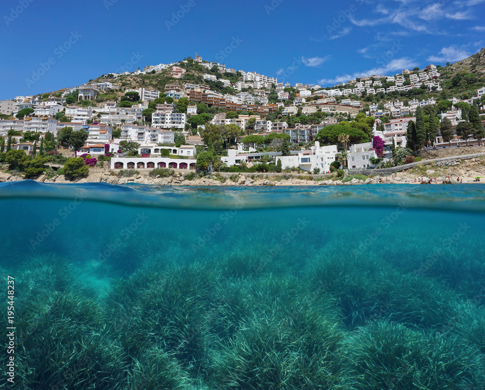 Spain coastline with buildings on the Costa Brava and neptune grass meadow underwater, split view above and below water surface, Mediterranean sea, Roses, Catalonia