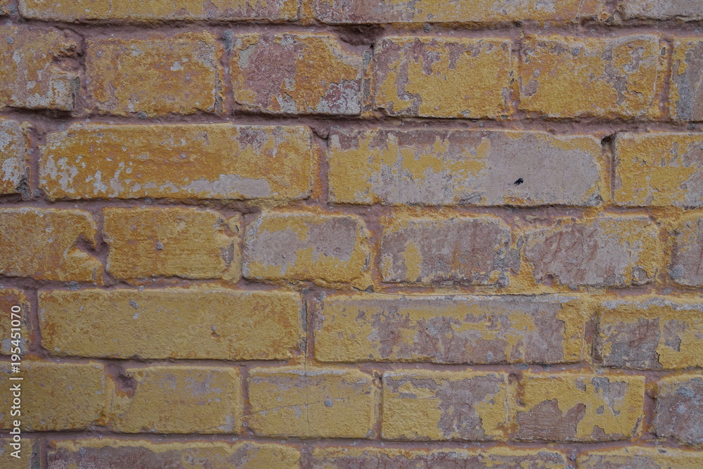 Fototapeta premium Remains of old yellow paint on brick wall