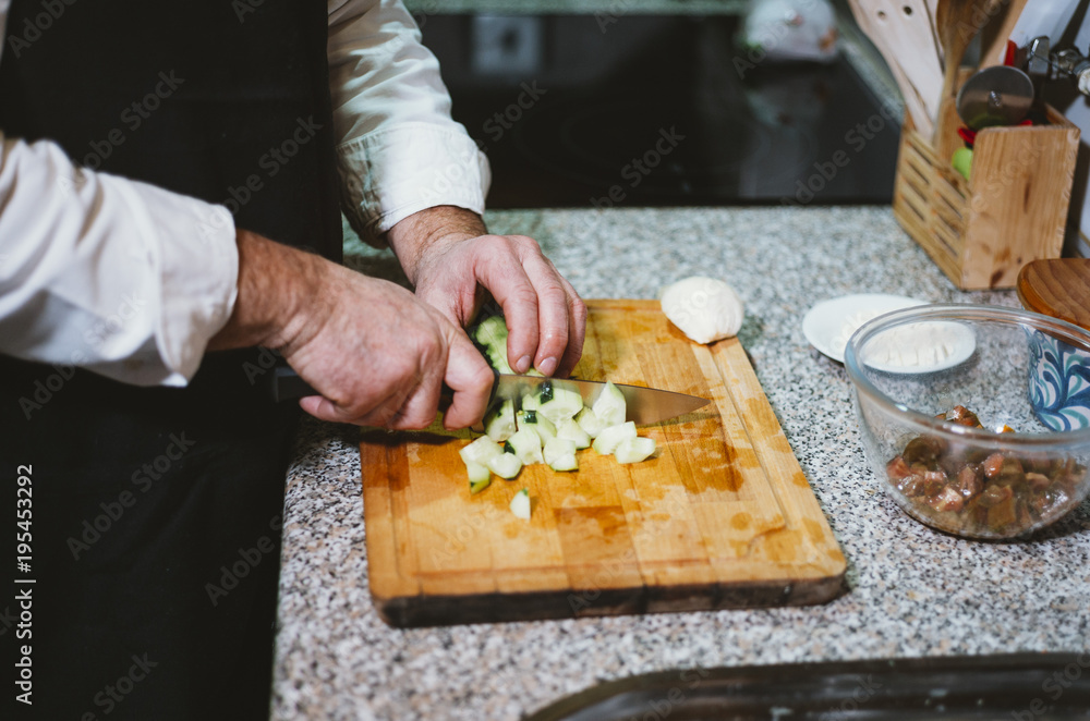 Man of 59 year old cutting vegetables in the kitchen of his house.