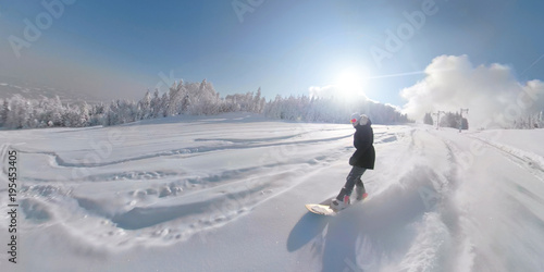 SUN FLARE Freeride snowboard girl riding freshly fallen snow in sunny ski resort
