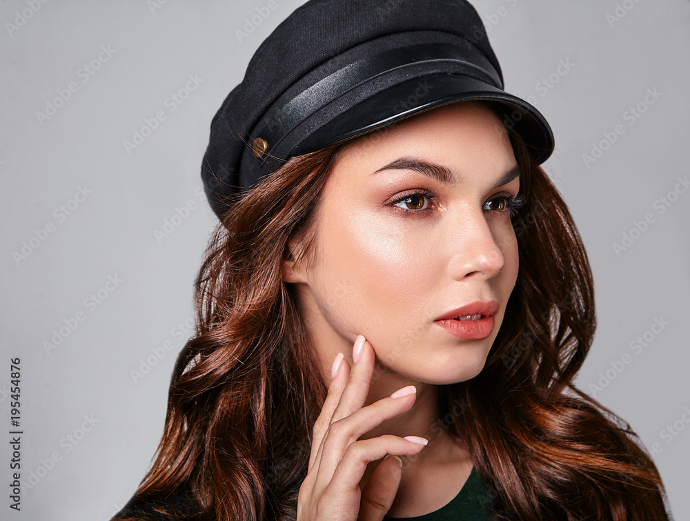 Portrait of young stylish laughing girl model in black casual summer clothes in cap with natural makeup isolated on gray background. Looking at camera Portrait of young stylish laughing girl model in black casual summer clothes in cap with natural makeup isolated on gray background. Looking at camera