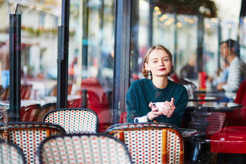 Young elegant woman drinking coffee in cafe in Paris, France