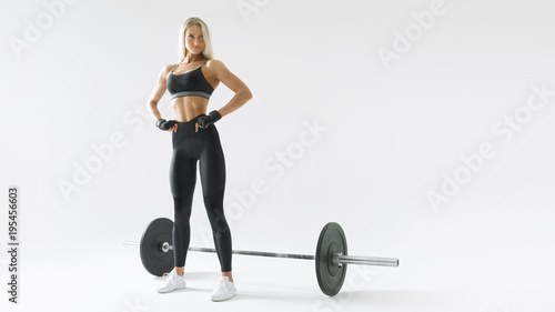 Confident young blonde woman with barbell concept black and white photo Female athlete before exercising with heavy weights at gym Female performing deadlift exercise with weight bar.