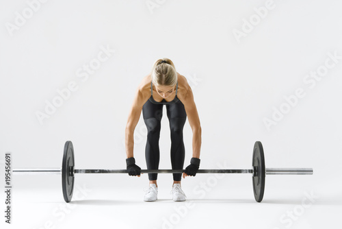 Fitness attractive woman preparing to practice deadlift with heavy weights Female bodybuilder doing heavy weight lifting work out on white background Horizontal picture