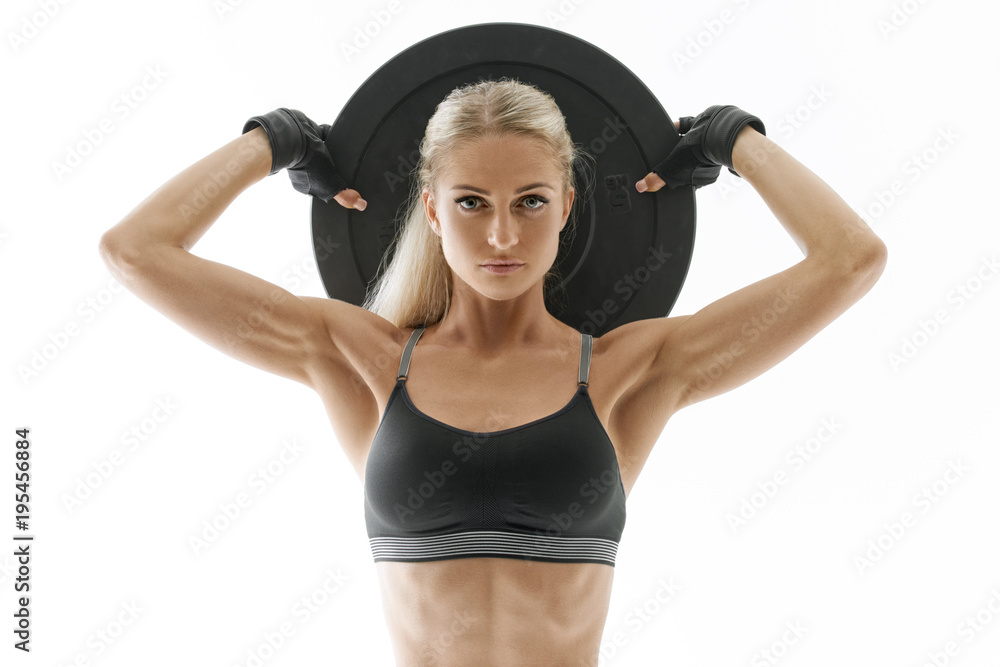 © USM Photography - Fit power athletic confident young woman crossfit exercise with heavy weight barbell plate rising hand Perfect fit athletic girl posing with barbell plate strong lat muscle shoulders biceps triceps.