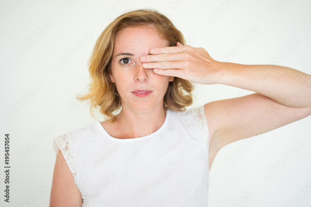 Serious calm woman covering one eye