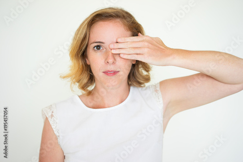 Serious calm woman covering one eye
