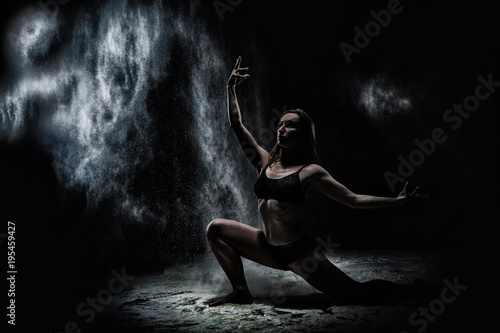 Girl dansing with flour on black background © keleny