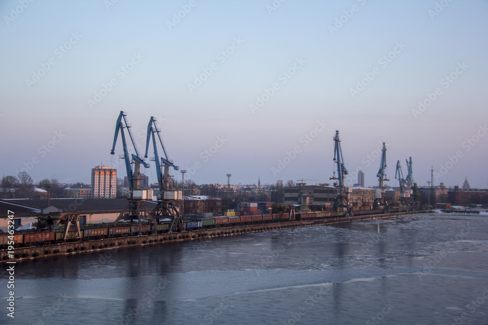 Freight shipping containers and gas oil tanks at the docks. in import export and business logistic. Cargo ship docked at at the port. Cargo cranes by winter evening in the Port Riga, Latvia.