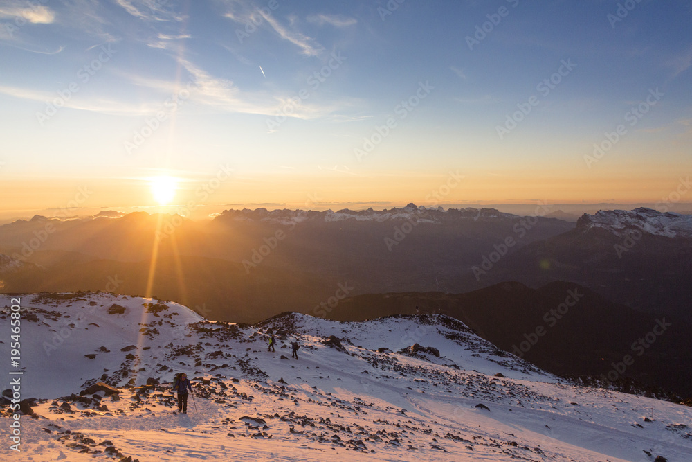 Tourists climb the mountain at the sunset in the French Alps