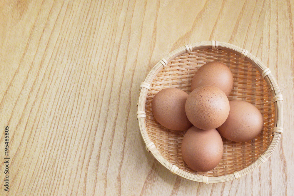 Eggs in a wooden basket on wooden floor background Eggs in a wooden basket on wooden floor background