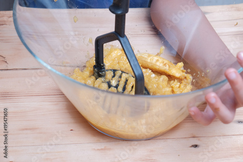 Young Asian boy mash the bananas in large bowl. photo