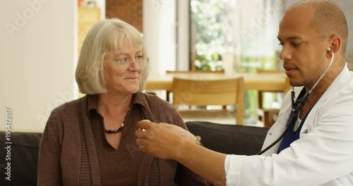 Wallpaper Mural 4K Young friendly doctor on home care visit listening to heart rate of cheerful senior lady. Slow motion Torontodigital.ca