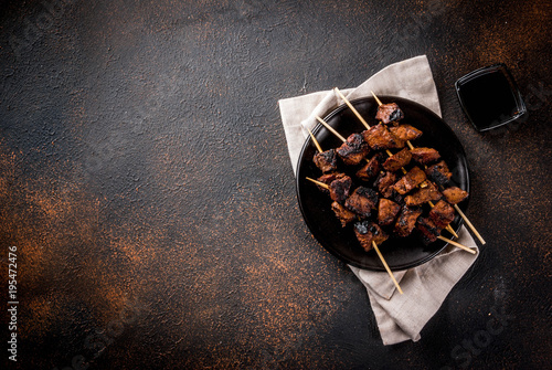 Grilled beef liver on skewers, with teriyaki or soy sauce, yakitori, dark rusty table copy space top view