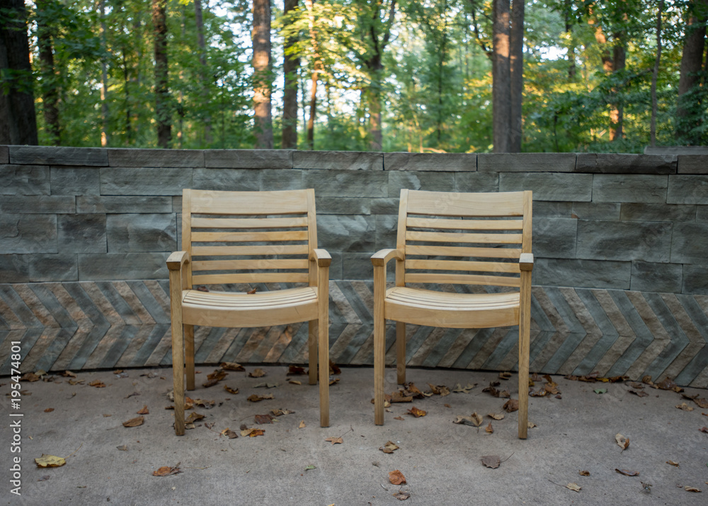 Two Wooden Arm Chairs Against Stone Wall