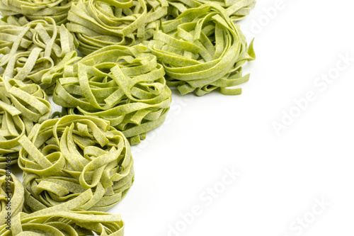 Raw spinach fettuccine pasta background isolated on white. photo