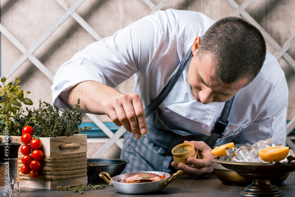 Chef sprinkling spices on dish in commercial kitchen. Gourmet Restaurant Chef sprinkling spices on dish in commercial kitchen. Gourmet Restaurant