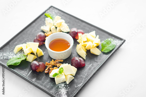 Assorted cheeses with honey and nuts in the black plate in restaurant