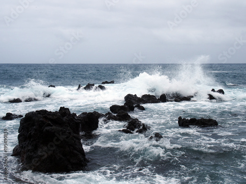 seascape with stormy dramatic waves breaking over coastal rocks with white surf