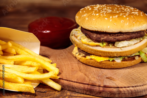 Delicious big hamburger with french fries and ketchup on wooden table