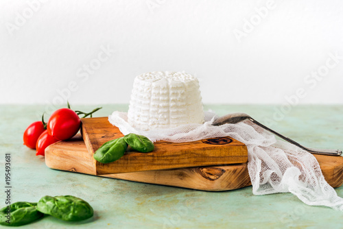 ricotta su tagliere di legno con pomodori e foglie di spinaci