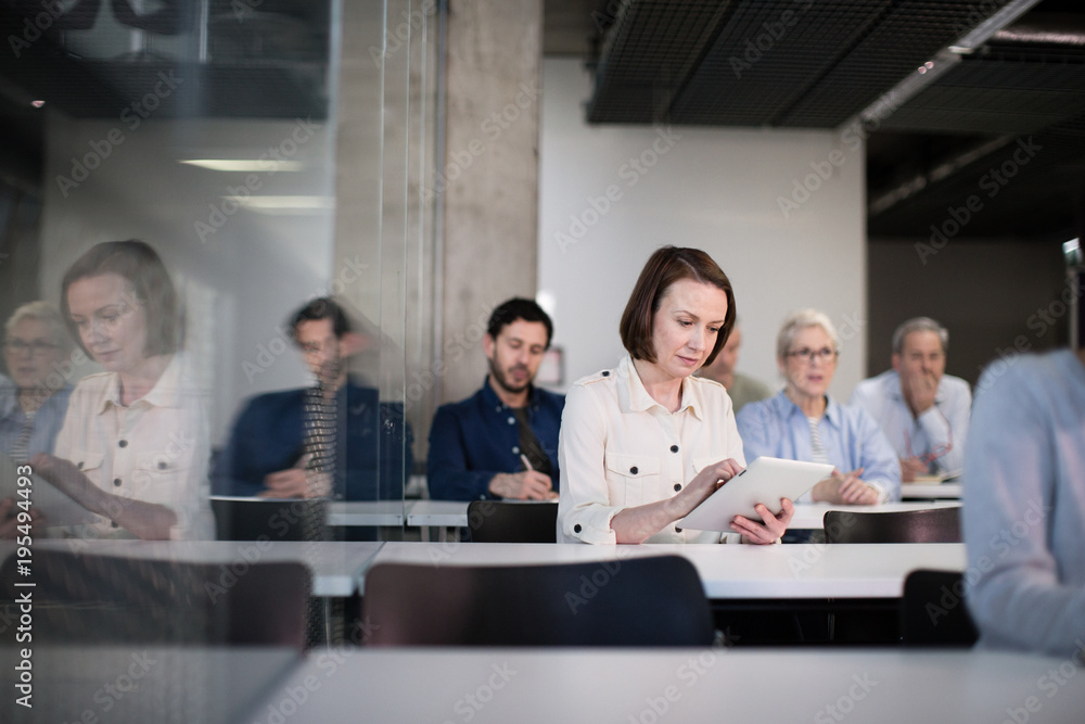 © ReeldealHD images - Mature student taking notes on digital tablet in a lecture