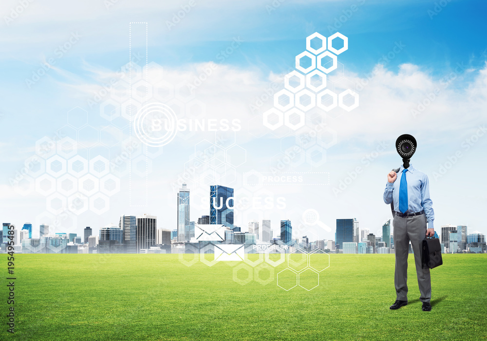 Camera headed man standing on green grass against modern cityscape Camera headed man standing on green grass against modern cityscape