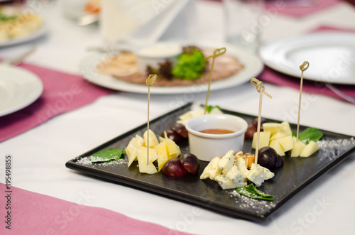 Assorted cheeses with honey and nuts in the black plate in restaurant