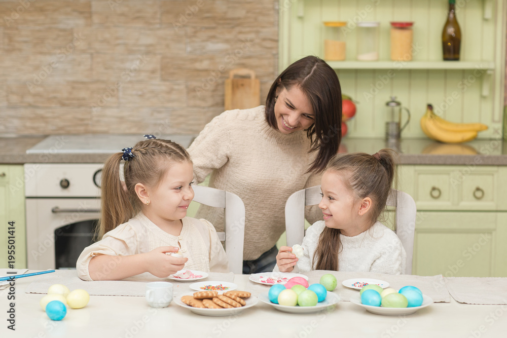 Fototapeta premium little sisters with mom playing with Easter eggs on Easter day