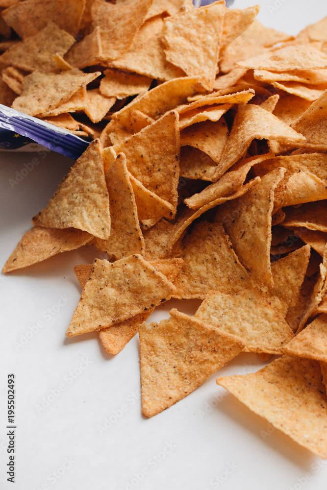 Pile of delicious crispy nachos of out pack on white background, traditional Mexican cuisine Pile of delicious crispy nachos of out pack on white background, traditional Mexican cuisine