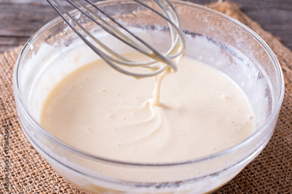 Dough for crepes or pancakes in glass bowl on the wooden table Dough for crepes or pancakes in glass bowl on the wooden table