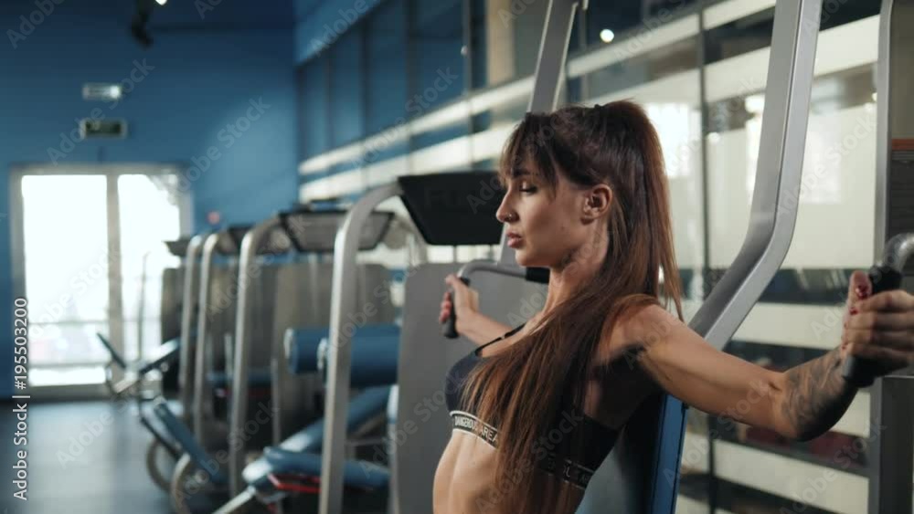 Brutal athletic woman pumping up muscules with dumbbells, training girl with barbell in gym indoor Brutal athletic woman pumping up muscules with dumbbells, training girl with barbell in gym indoor