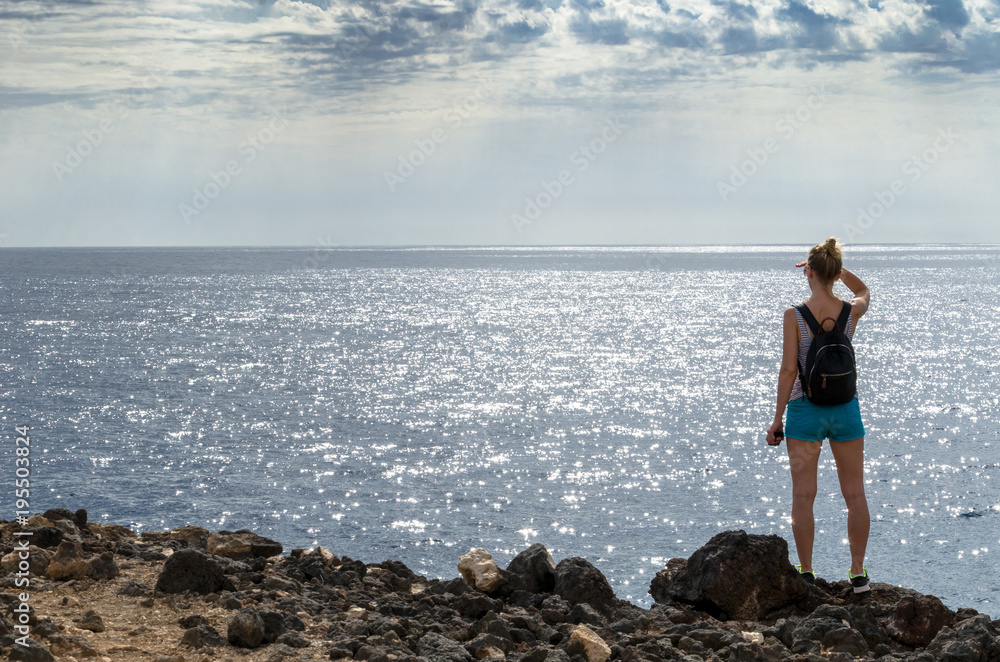 Rear view of a woman staring into the sea. Photo taken in Tenerife by the Atlantic Ocean.
