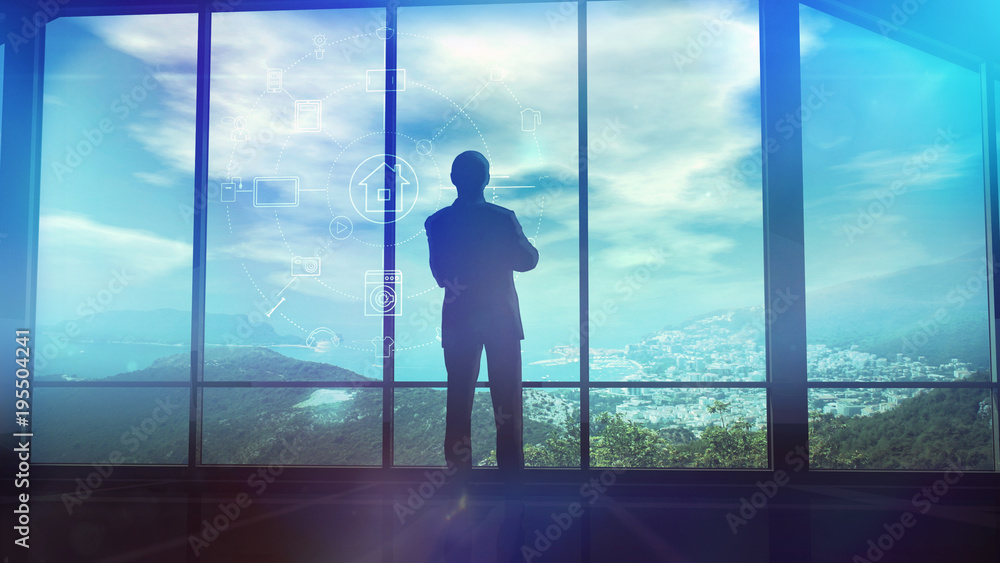 A man is standing by the window viewing IOT infographics elements A man is standing by the window viewing IOT infographics elements