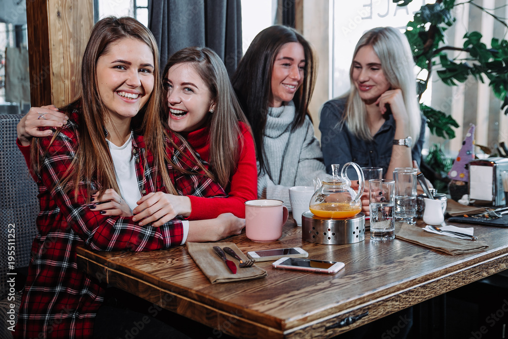 four friends in the cafe look at the camera and laugh four friends in the cafe look at the camera and laugh