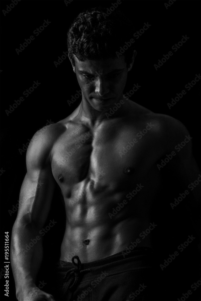 Naklejka premium Highly retouched black and white fitness model and bodybuilder, Looking and posing abs and chest. concept of power, strength and self-confidence. black background.