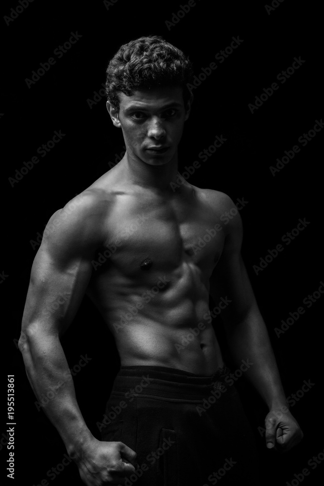 Highly retouched black and white fitness model and bodybuilder, Looking and posing abs and chest. concept of power, strength and self-confidence. black background. Highly retouched black and white fitness model and bodybuilder, Looking and posing abs and chest. concept of power, strength and self-confidence. black background.