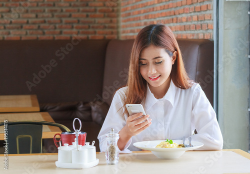 Happy woman having lunch at restaurant and calling on smartphone