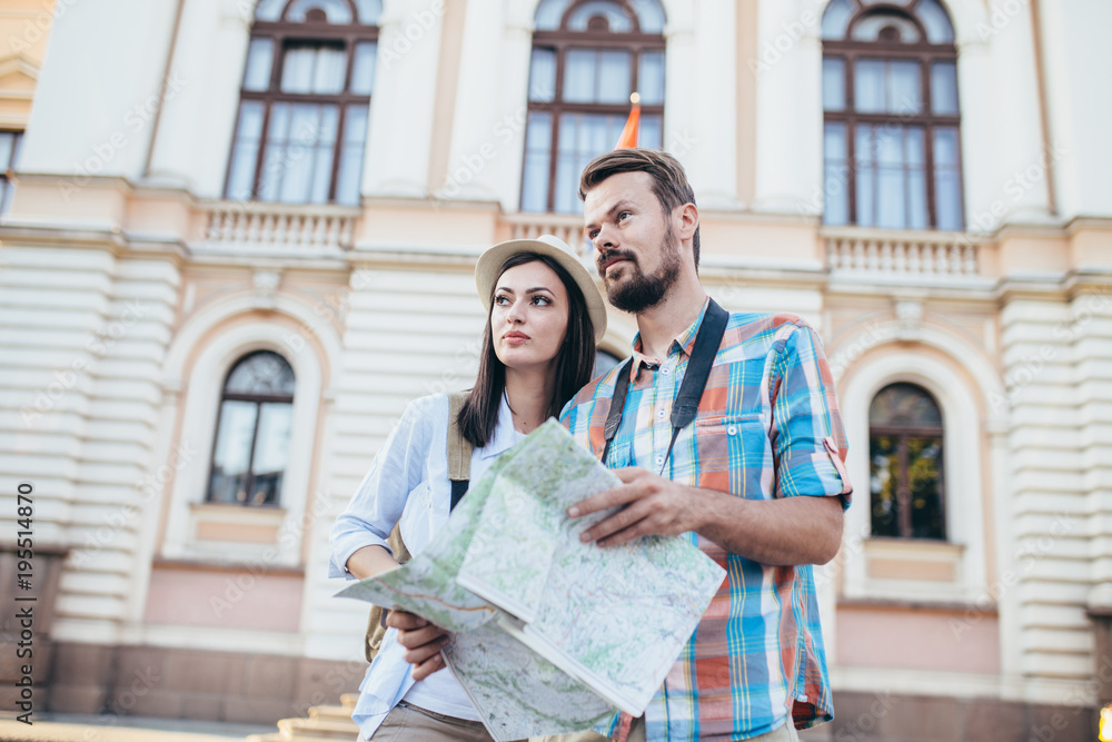 Fototapeta premium Tourist couple traveling and using map/Tourist couple exploring city.