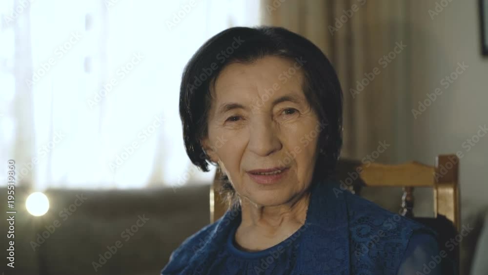 Portrait of happy old woman in dress smiling at camera in the room Portrait of happy old woman in dress smiling at camera in the room