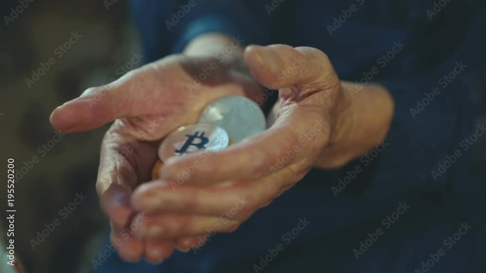 Wrinkled old female hands holding many golden and silver bitcoins Wrinkled old female hands holding many golden and silver bitcoins