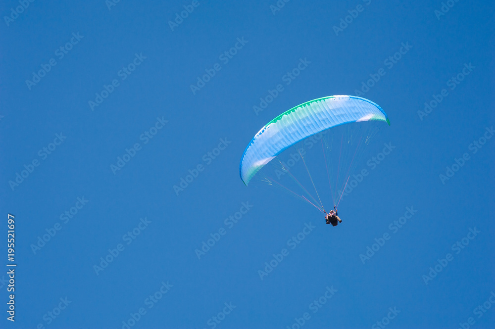 Alone paraglider flying on the background of blue sky. Paragliding in the sky on a sunny day. Alone paraglider flying on the background of blue sky. Paragliding in the sky on a sunny day.